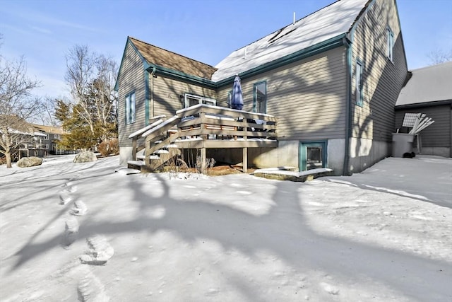 snow covered back of property featuring a wooden deck