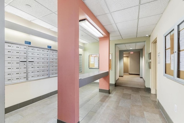 hall featuring a paneled ceiling and mail boxes