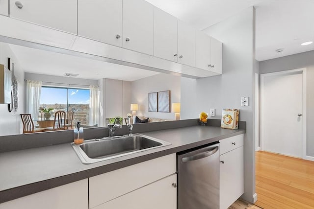 kitchen with sink, stainless steel dishwasher, light wood-type flooring, and white cabinets