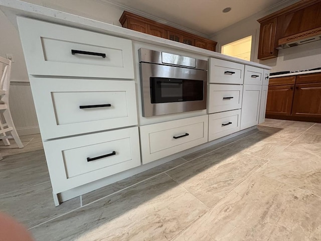 interior space with crown molding, wall oven, light countertops, under cabinet range hood, and black cooktop
