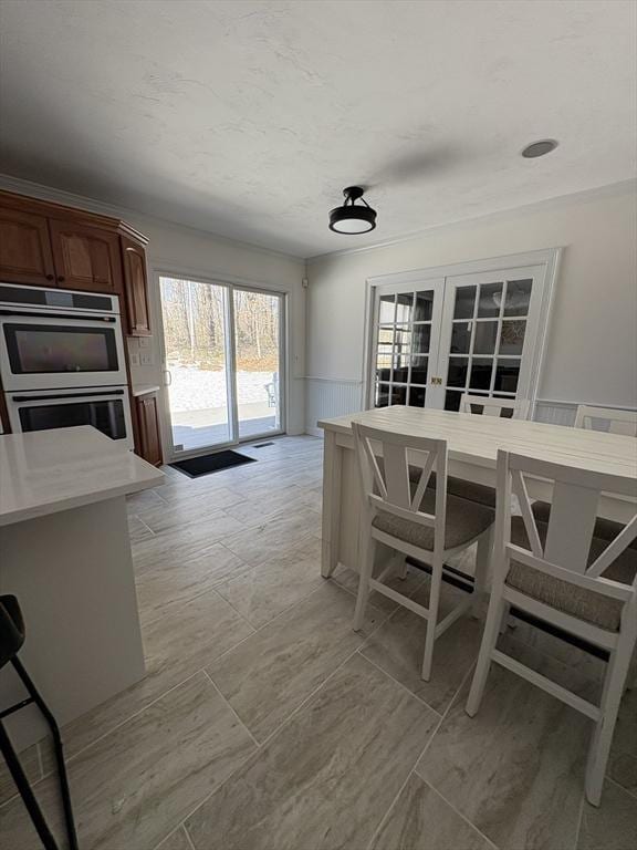 dining room featuring a wainscoted wall and french doors