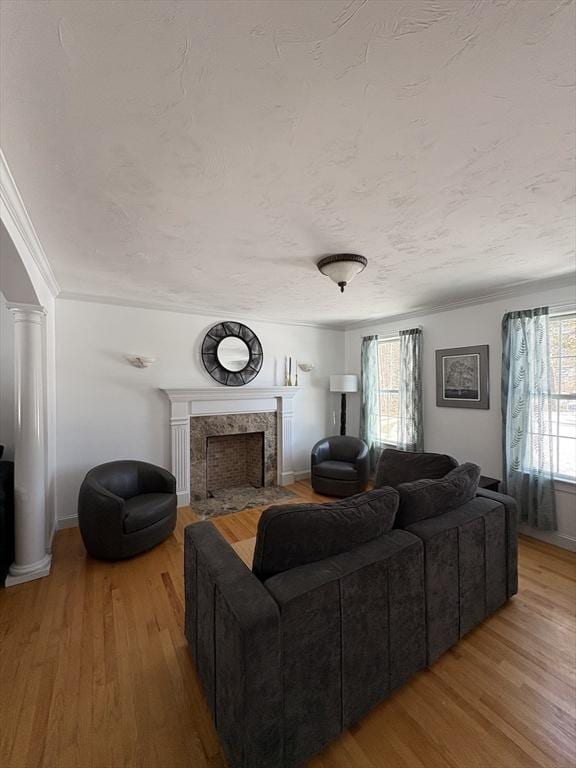living room featuring a premium fireplace, wood finished floors, baseboards, and ornamental molding