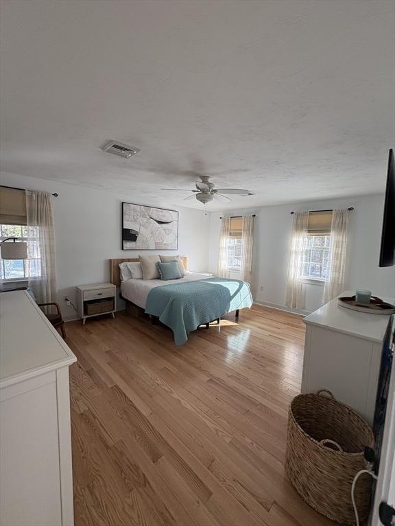 bedroom with visible vents, light wood finished floors, and a ceiling fan