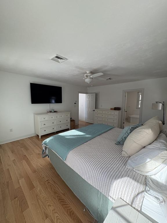 bedroom with baseboards, a ceiling fan, light wood-style floors, and visible vents