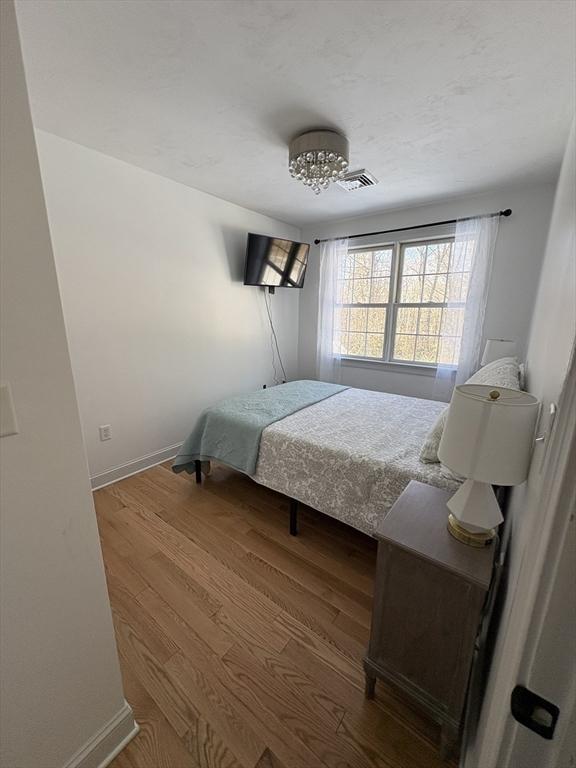 bedroom featuring baseboards, wood finished floors, and visible vents