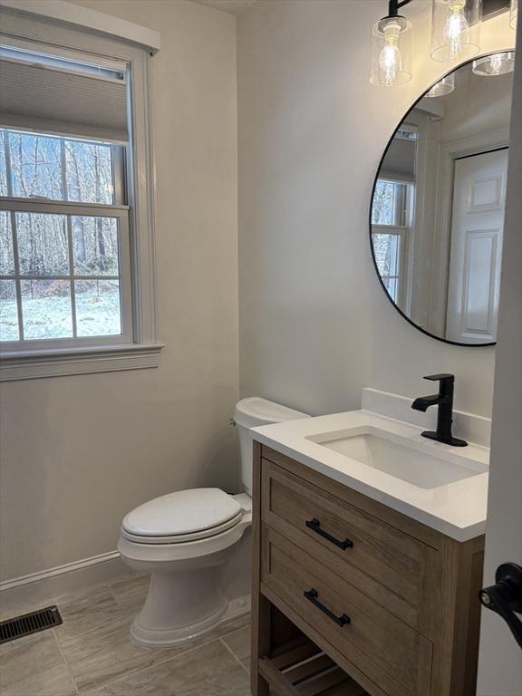 bathroom featuring tile patterned floors, visible vents, toilet, vanity, and baseboards