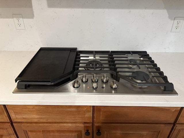 details with stainless steel gas stovetop, light countertops, and brown cabinets