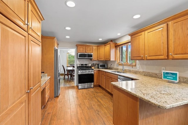 20 Highwood Way, North Andover, MA 01845 - kitchen featuring appliances with stainless steel finishes, a sink, a peninsula, decorative backsplash, and light stone countertops