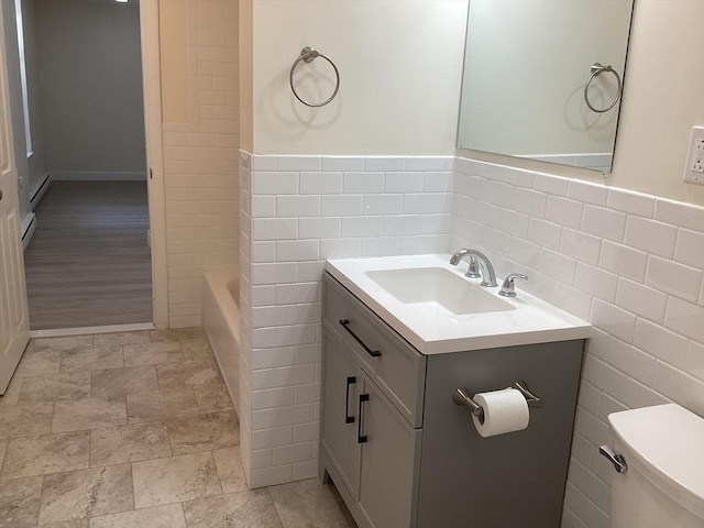 566 Commonwealth Ave # 101, Boston, MA 02215 - bathroom with tile walls, vanity, a bathtub, a wainscoted wall, and baseboard heating