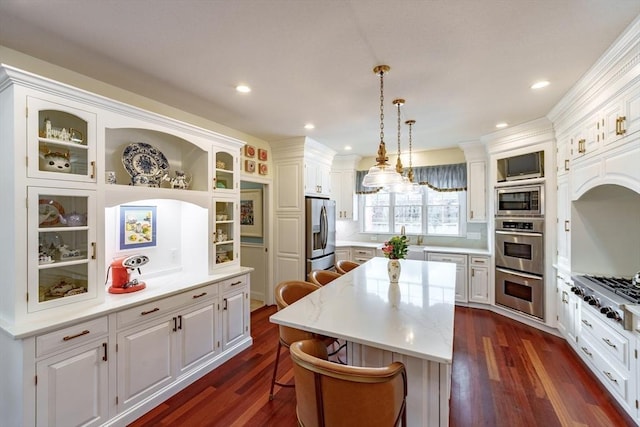 kitchen featuring a breakfast bar, hanging light fixtures, stainless steel appliances, white cabinets, and a kitchen island