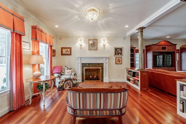 living area with crown molding, wood-type flooring, a high end fireplace, and ornate columns