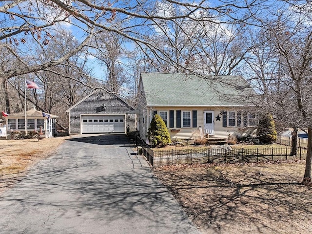 cape cod house with a fenced front yard and a detached garage