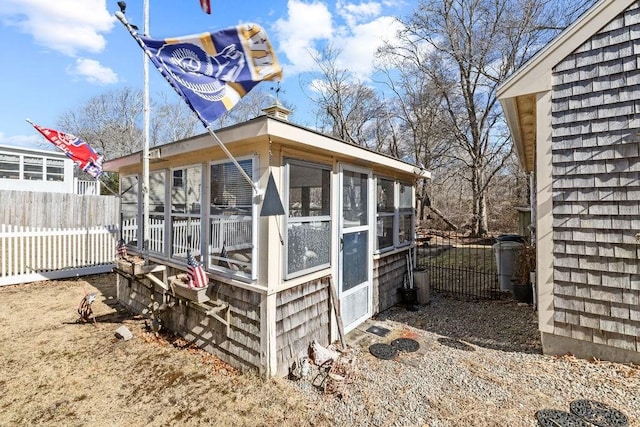 view of outbuilding featuring a sunroom and fence