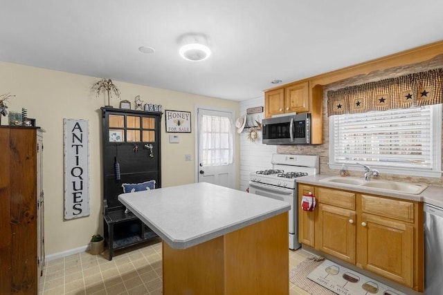 kitchen featuring a sink, light countertops, appliances with stainless steel finishes, decorative backsplash, and a center island