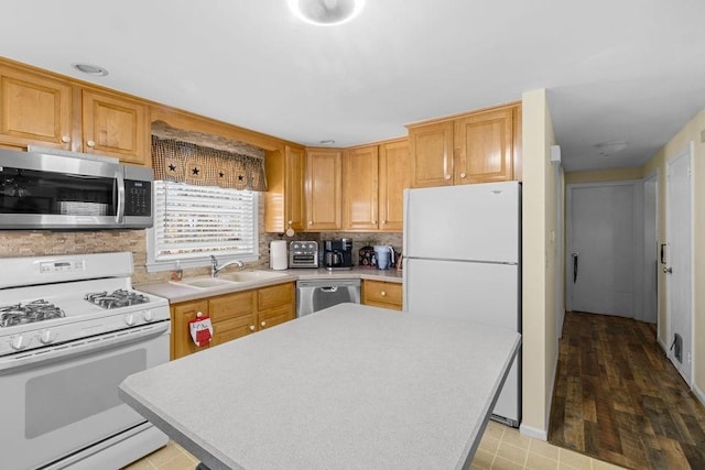 kitchen with a kitchen island, appliances with stainless steel finishes, backsplash, light countertops, and a sink