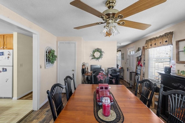 dining area featuring a textured ceiling, ceiling fan, wood finished floors, and baseboards