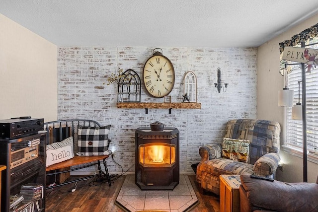 living area with a wood stove, a textured ceiling, and wood finished floors