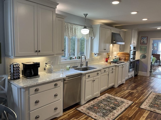 kitchen featuring pendant lighting, sink, dark hardwood / wood-style flooring, stainless steel appliances, and wall chimney range hood