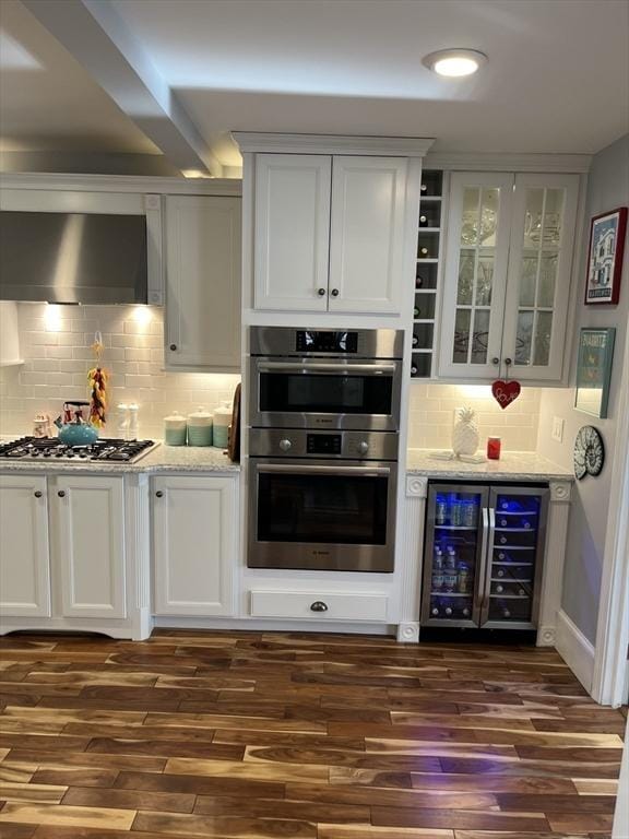 bar featuring wine cooler, white cabinetry, appliances with stainless steel finishes, and wall chimney range hood