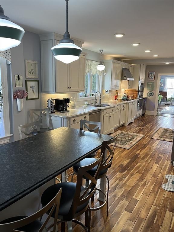 kitchen with dark hardwood / wood-style floors, decorative light fixtures, tasteful backsplash, sink, and white cabinets