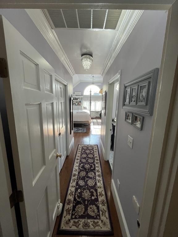 corridor featuring ornamental molding, dark hardwood / wood-style floors, and a chandelier