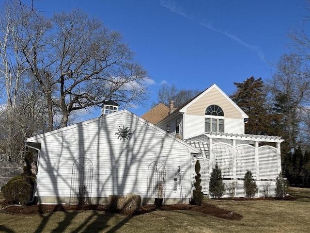 view of side of property featuring a yard and a pergola