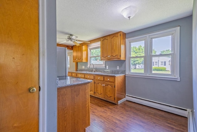 121 Donlyn Dr, Chicopee, MA 01013 - kitchen featuring baseboard heating, a textured ceiling, brown cabinetry, dark wood finished floors, and freestanding refrigerator