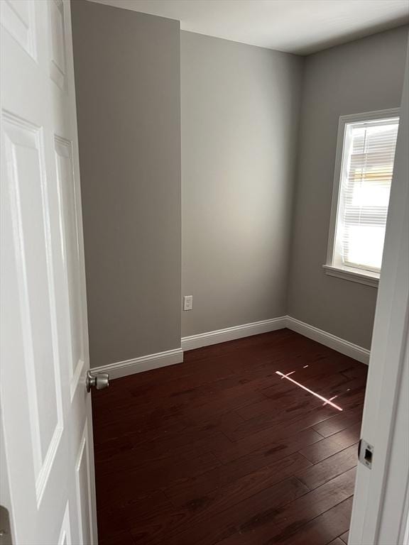 spare room with baseboards and dark wood finished floors