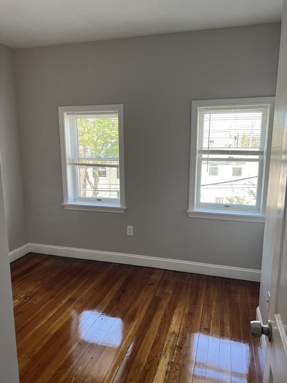 unfurnished room featuring baseboards and dark wood-style floors