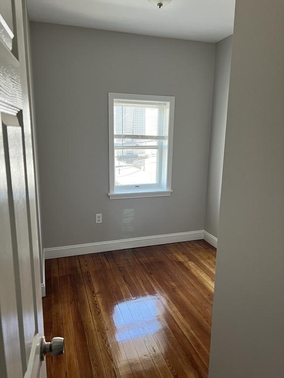 empty room with baseboards and wood-type flooring