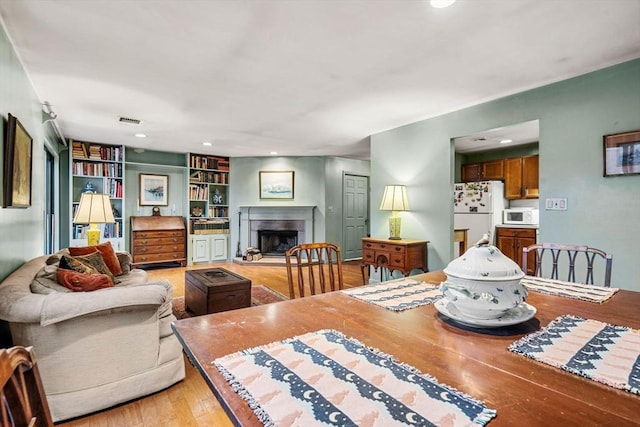 dining area with built in features, visible vents, light wood finished floors, recessed lighting, and a fireplace