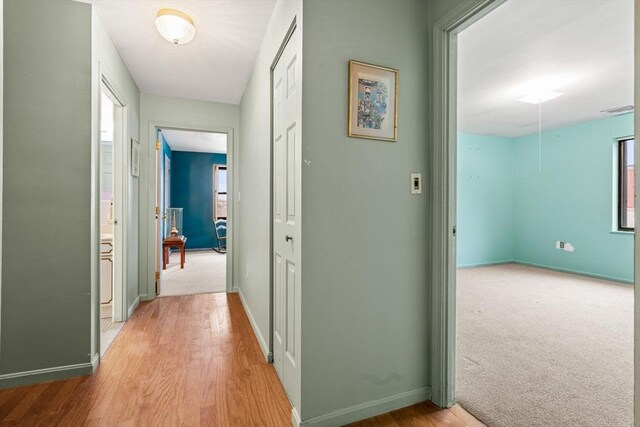 corridor featuring visible vents, baseboards, carpet, and wood finished floors