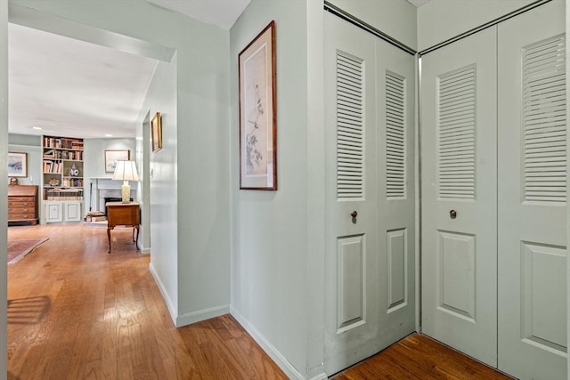 hall with baseboards, built in shelves, and hardwood / wood-style flooring