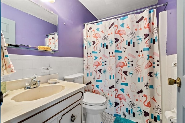 full bathroom with tile walls, toilet, wainscoting, tile patterned floors, and vanity