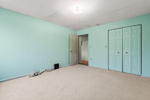 unfurnished bedroom with baseboards, carpet floors, and a closet