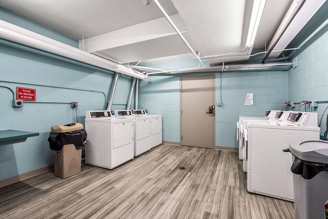 common laundry area featuring light wood finished floors, concrete block wall, and separate washer and dryer