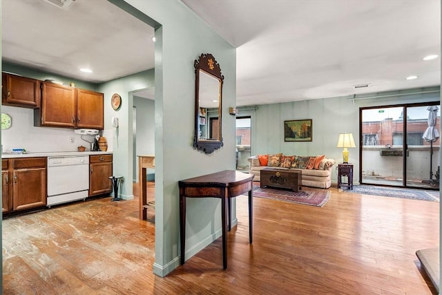 kitchen with open floor plan, dishwasher, light countertops, light wood-style flooring, and brown cabinetry