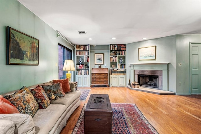 living room with recessed lighting, wood finished floors, visible vents, and a premium fireplace