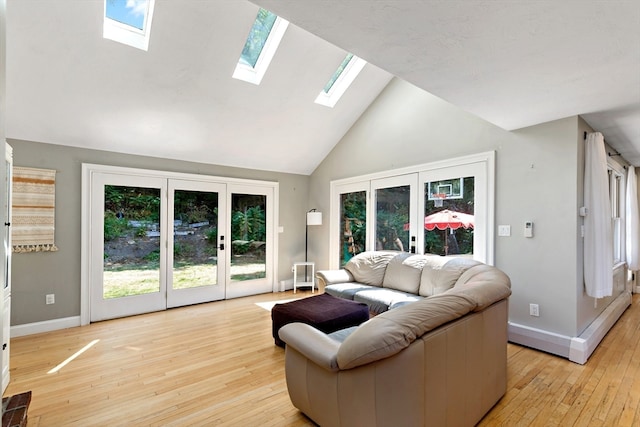 living room with light wood-type flooring, high vaulted ceiling, a skylight, and french doors