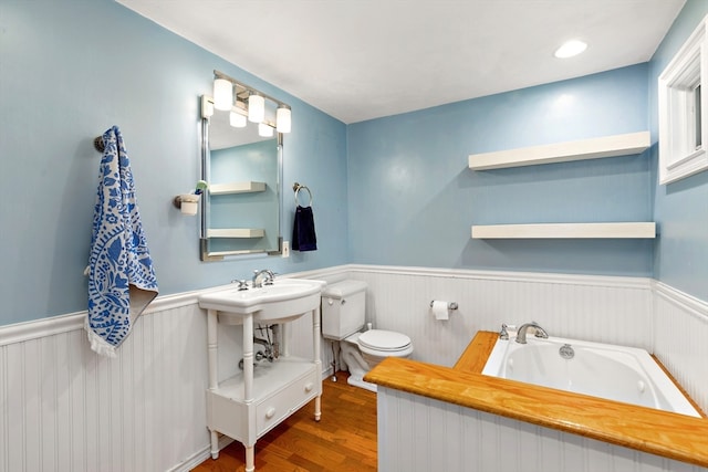 bathroom with a washtub, toilet, and hardwood / wood-style flooring