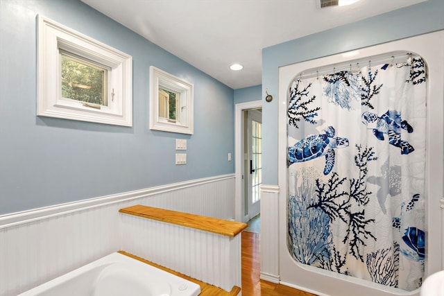 bathroom with a bath and hardwood / wood-style floors