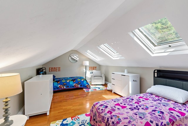 bedroom featuring lofted ceiling with skylight and light hardwood / wood-style flooring