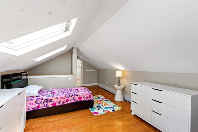 bedroom featuring vaulted ceiling with skylight, baseboard heating, and light hardwood / wood-style flooring