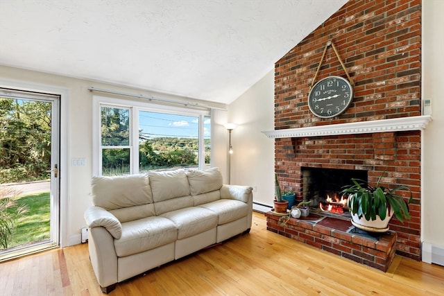 living room featuring light hardwood / wood-style flooring, a brick fireplace, vaulted ceiling, and a baseboard heating unit