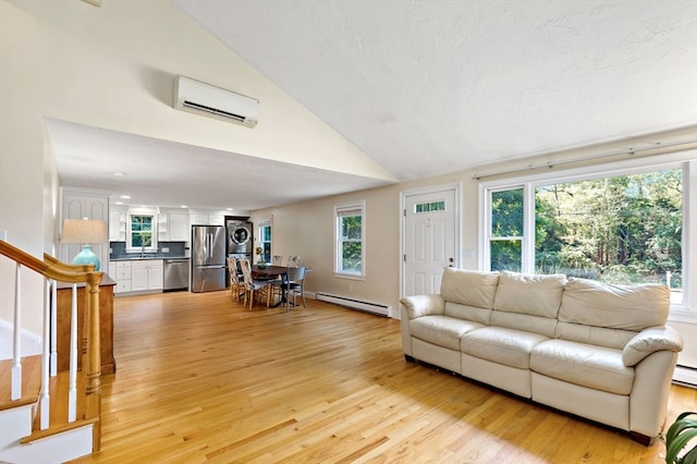 living room featuring stacked washer and dryer, light hardwood / wood-style floors, sink, an AC wall unit, and a baseboard radiator