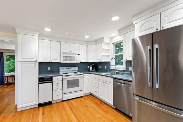 kitchen with appliances with stainless steel finishes, light wood-type flooring, sink, and a healthy amount of sunlight