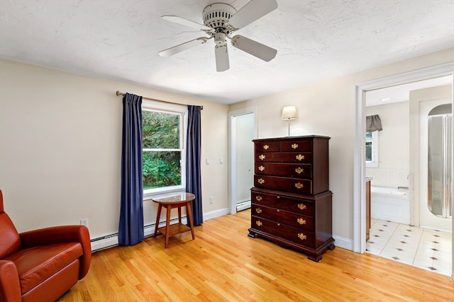 sitting room with a baseboard radiator, light wood-type flooring, and ceiling fan