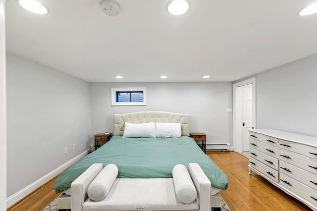 bedroom with a baseboard heating unit and light wood-type flooring