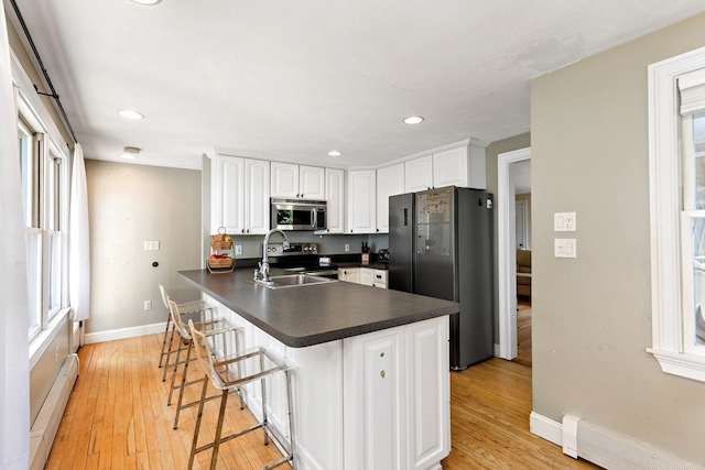 kitchen with white cabinets, appliances with stainless steel finishes, plenty of natural light, and a breakfast bar