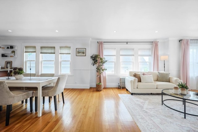 living room featuring radiator, ornamental molding, light wood-style flooring, baseboards, and recessed lighting